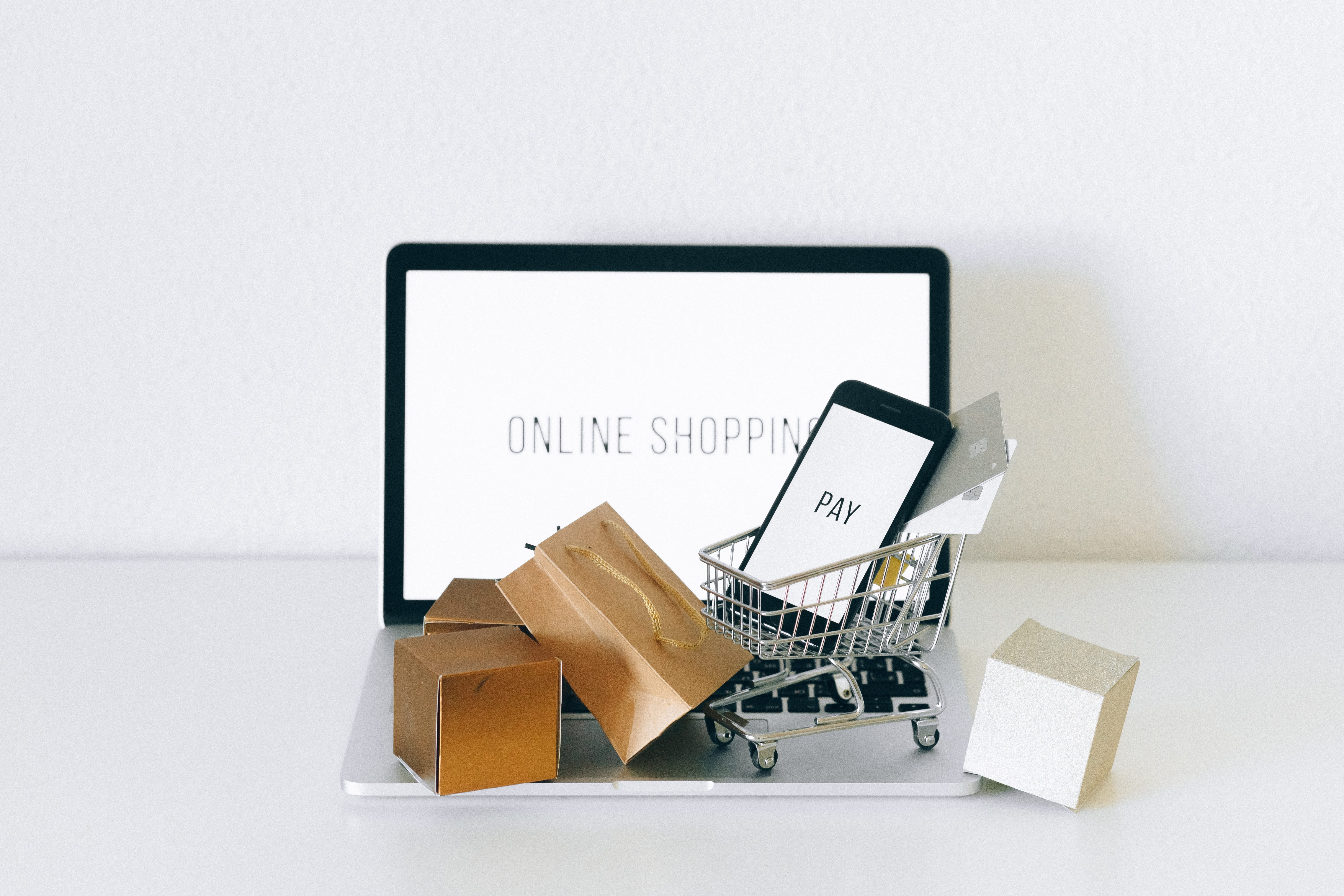 A laptop with boxes and a shopping cart on the desk.