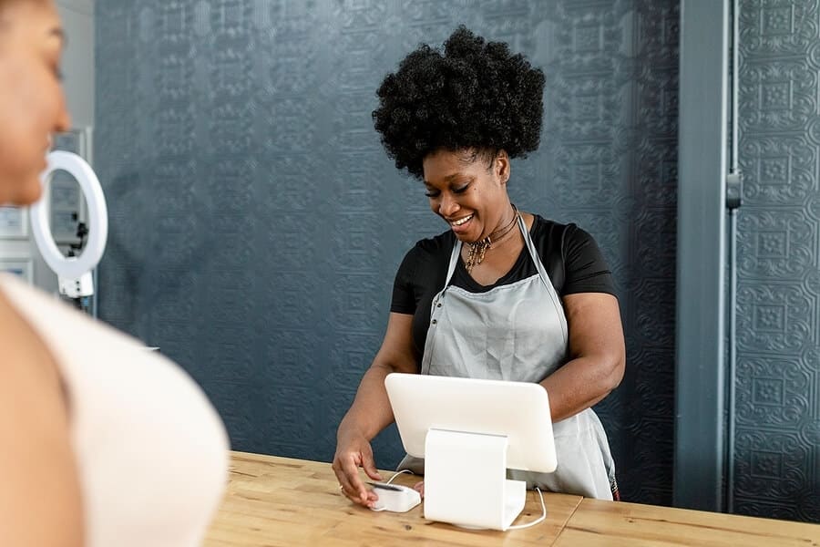 A woman in an apron is working on a tablet.