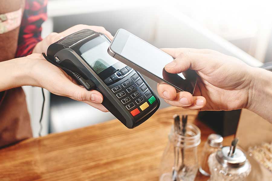 A person holding two phones and paying with their credit card.