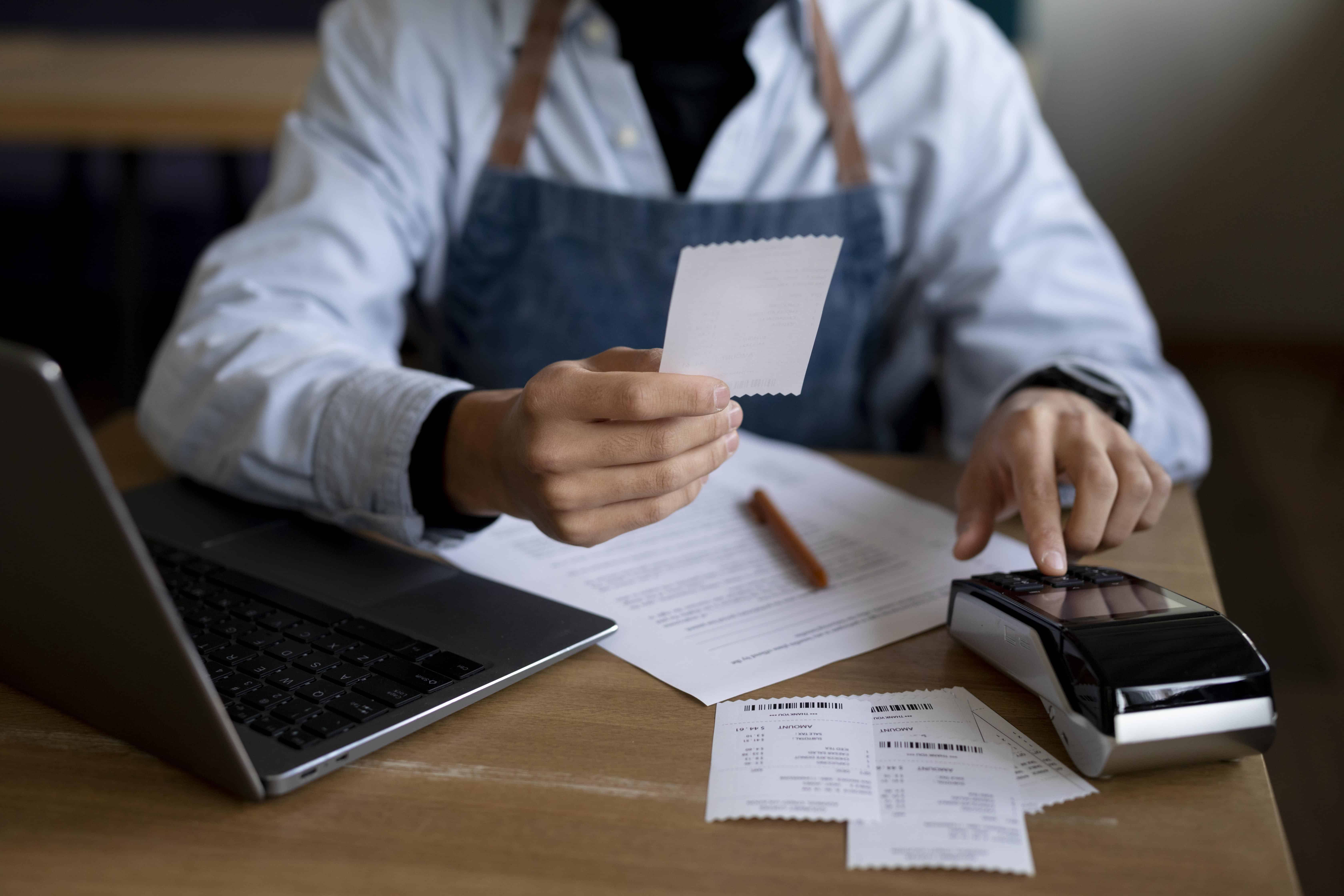 A person sitting at a table with papers and a calculator.