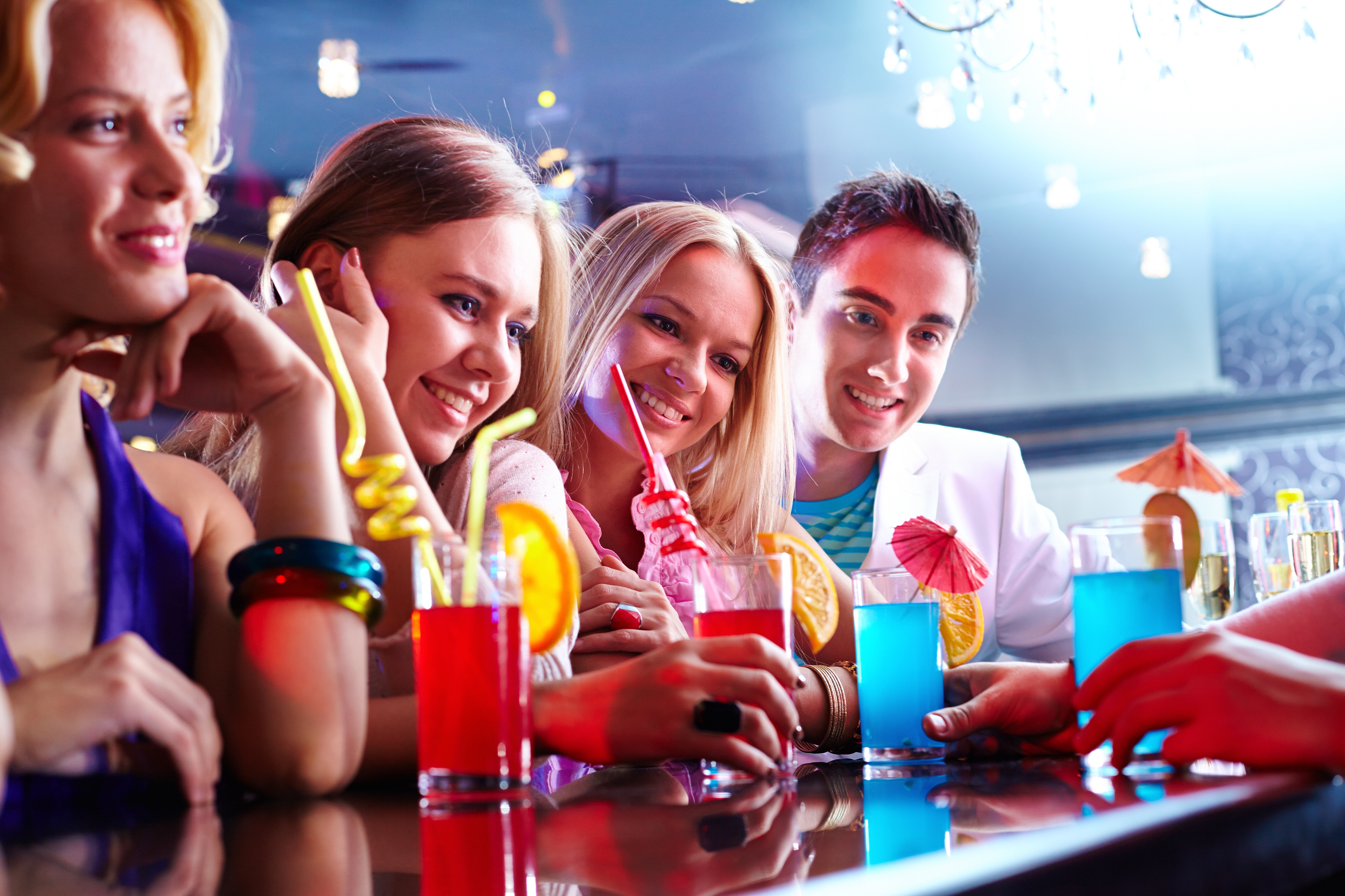A group of people sitting at a bar with drinks.