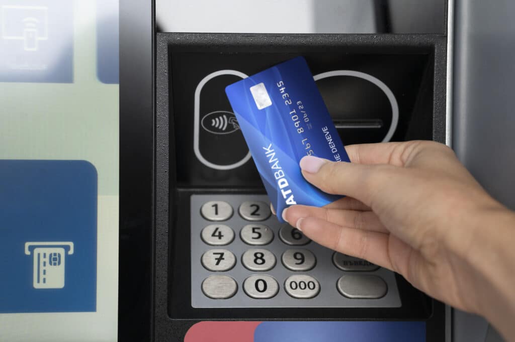 A person holding a credit card over an atm machine.