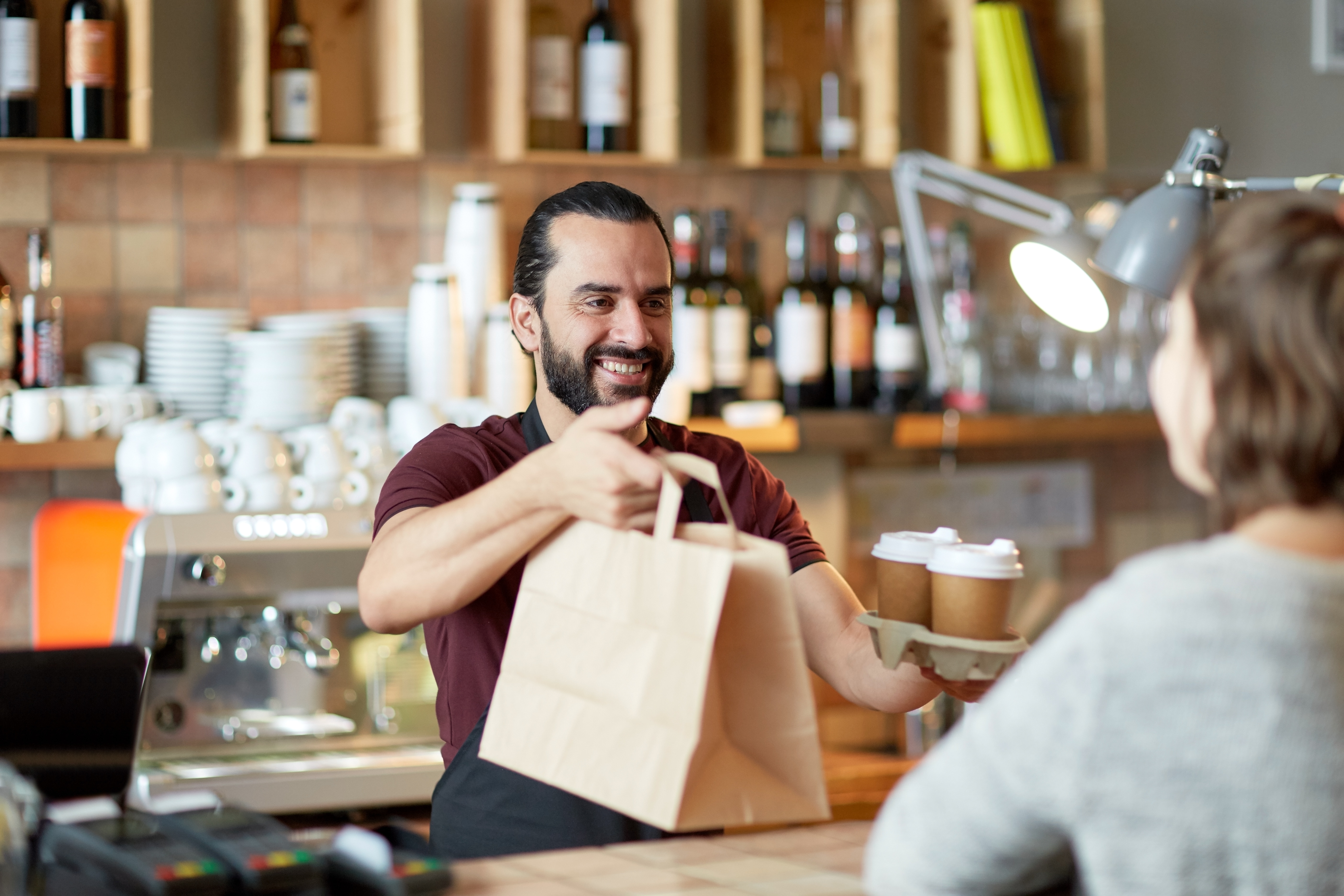 A man holding a bag of food at the counter.