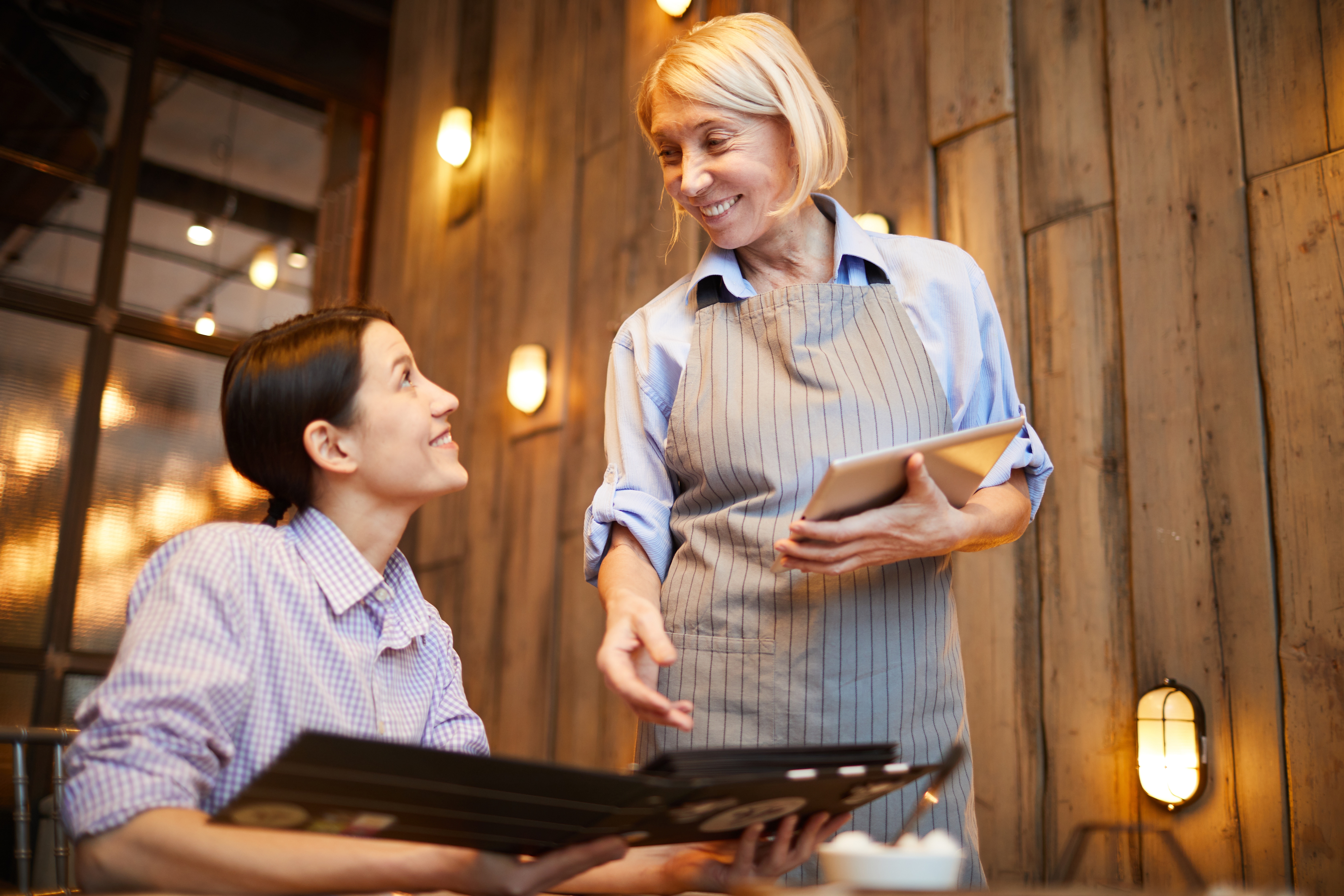 Two women are talking to each other in a restaurant.