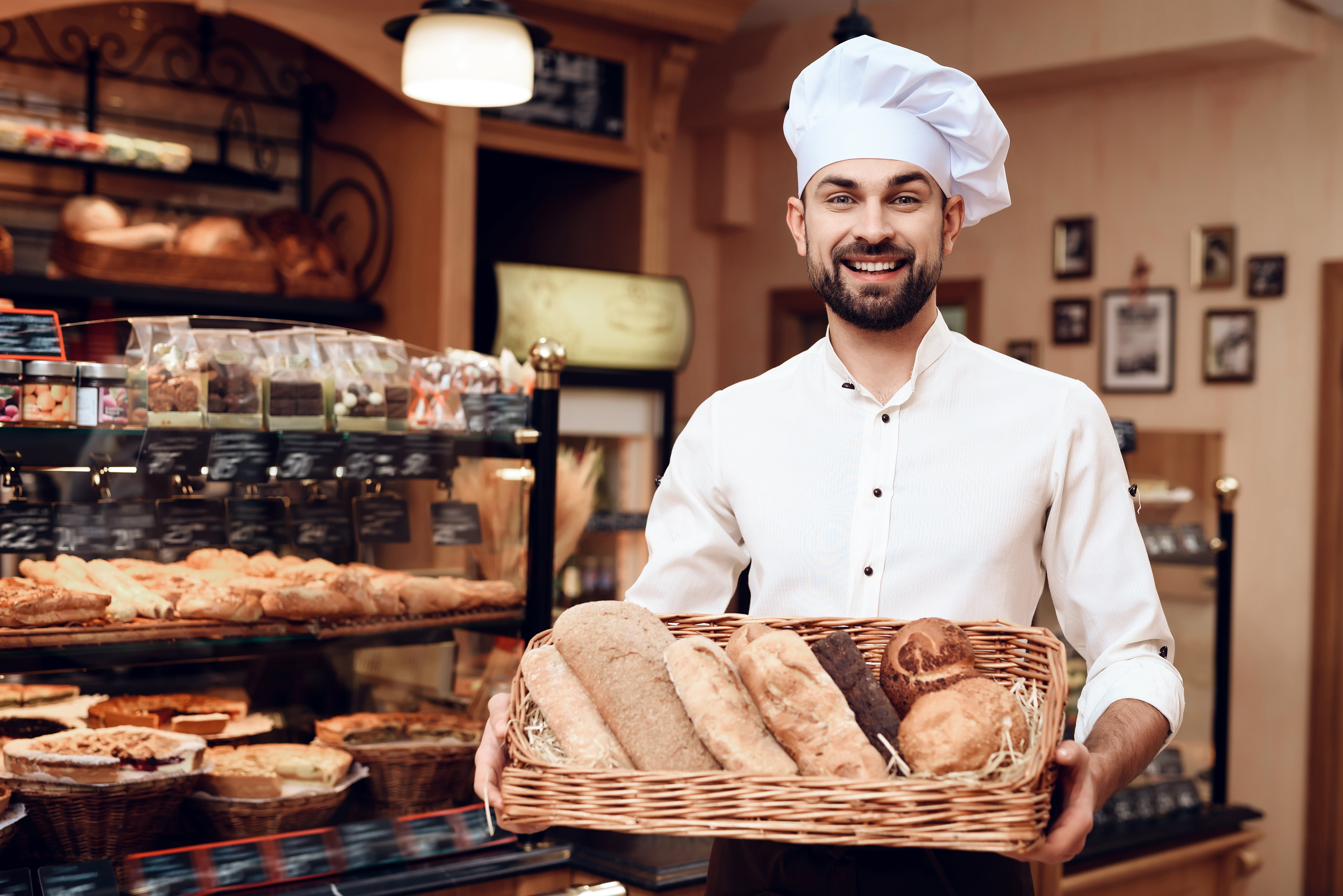 A man holding a basket of bread in a bakery.